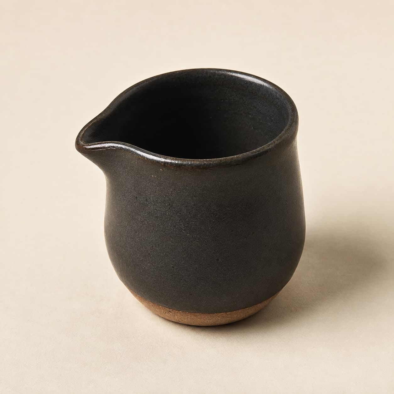 Milk Jug 150 ml — charcoal glazed stoneware with an unglazed clay foot ring.
