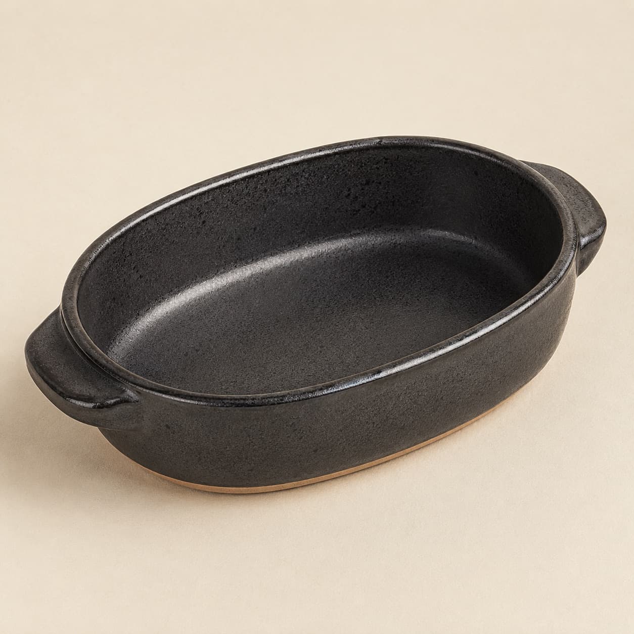 Oval Baker 30×18 — charcoal glazed stoneware with an unglazed clay foot ring.