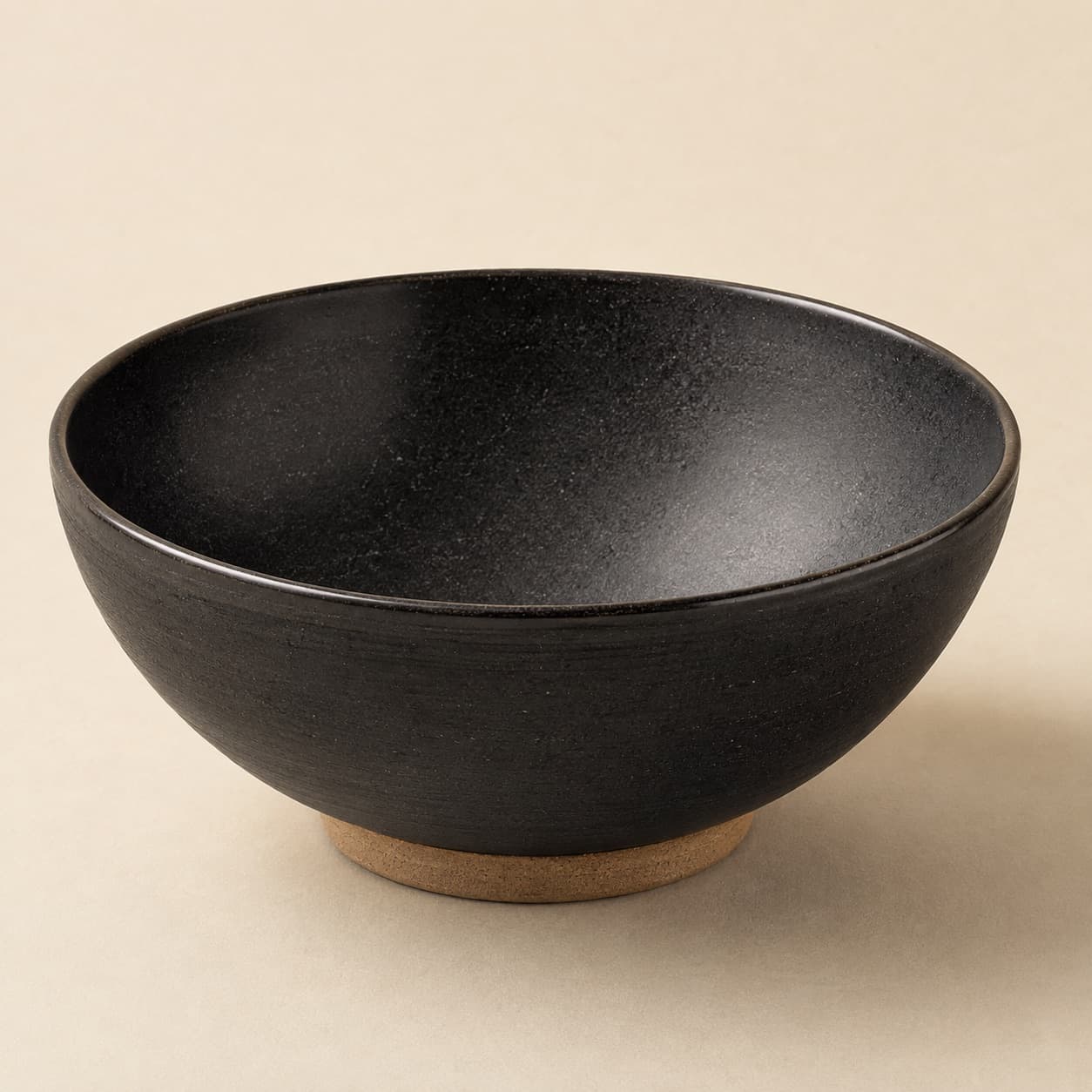 Salad Bowl Ø24 — charcoal glazed stoneware with an unglazed clay foot ring.