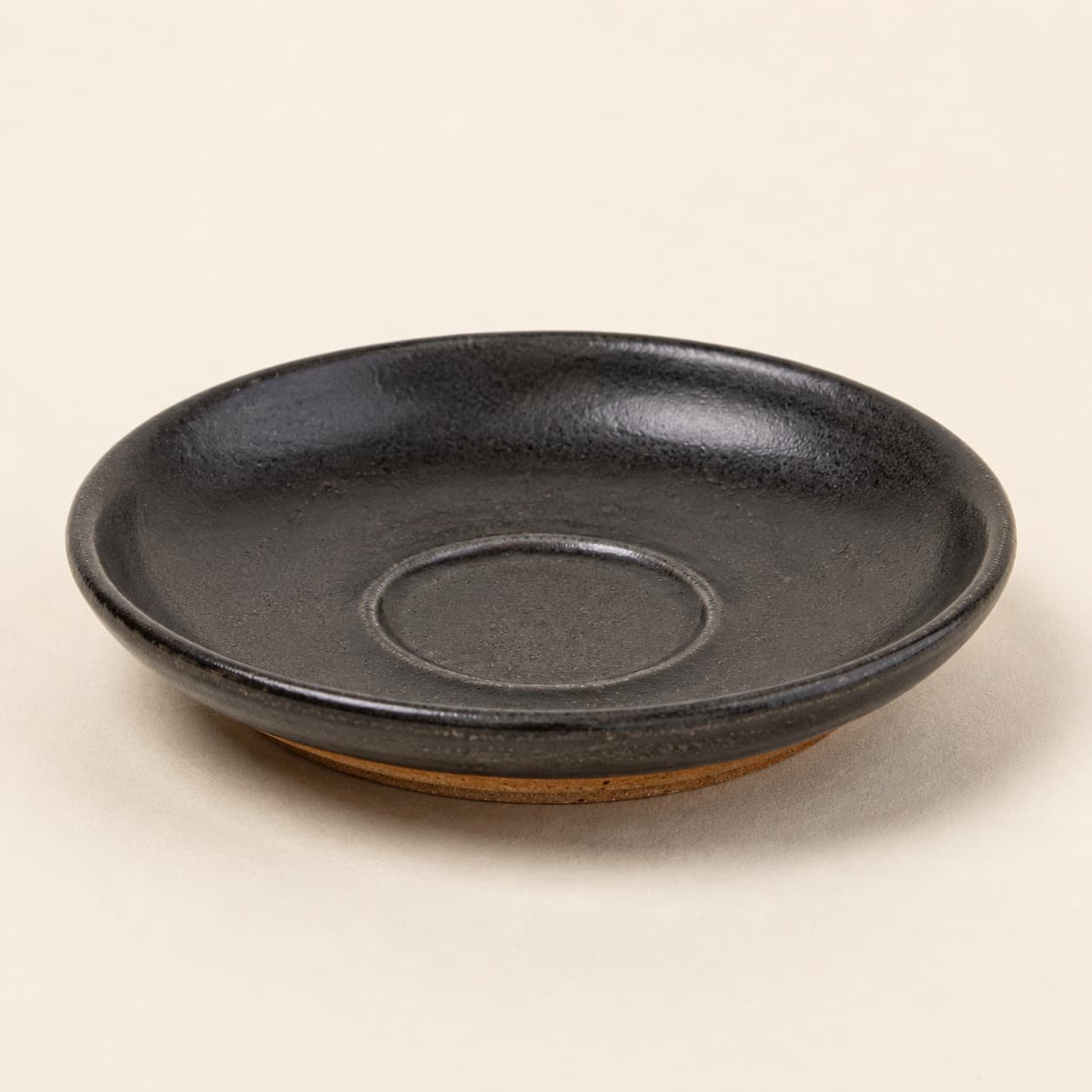 Saucer Ø14 — charcoal glazed stoneware with an unglazed clay foot ring.
