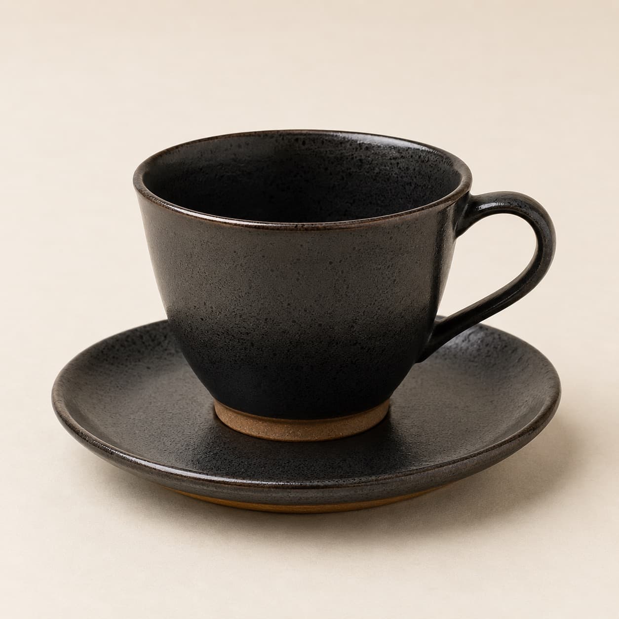 Tea Cup 250 ml + Saucer — charcoal glazed stoneware with an unglazed clay foot ring.